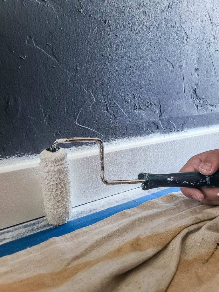 rolling Snowy Pine Behr white paint onto trim with dark gray walls