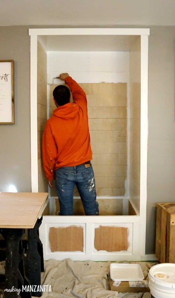 man painting small alcove white with Behr Paint Snowy Pine paint color