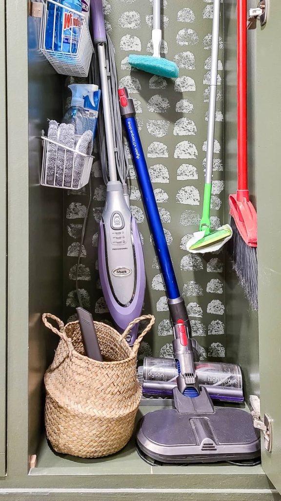 Close up image of a dyson and a wicker basket holding vacuum attachments inside a mudroom locker cabinet. 