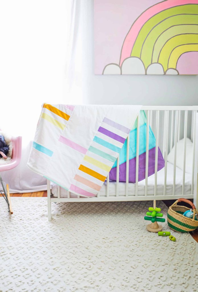 pastel colored crib quilt hanging on crib rail
