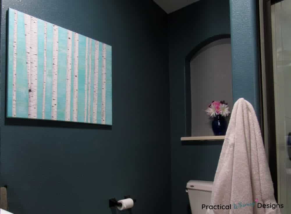painting of birch tree trunks hanging in a bathroom