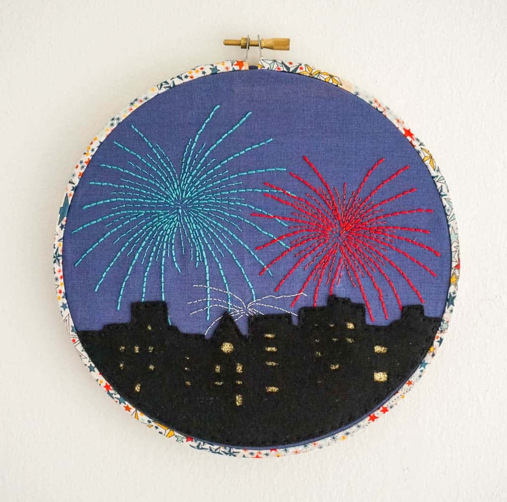 cross stitch pattern of fireworks over a cityscape