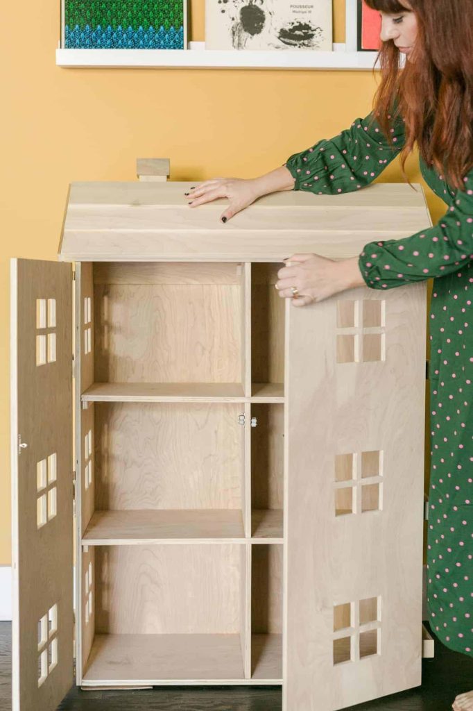 Woman standing next to large DIY dollhouse
