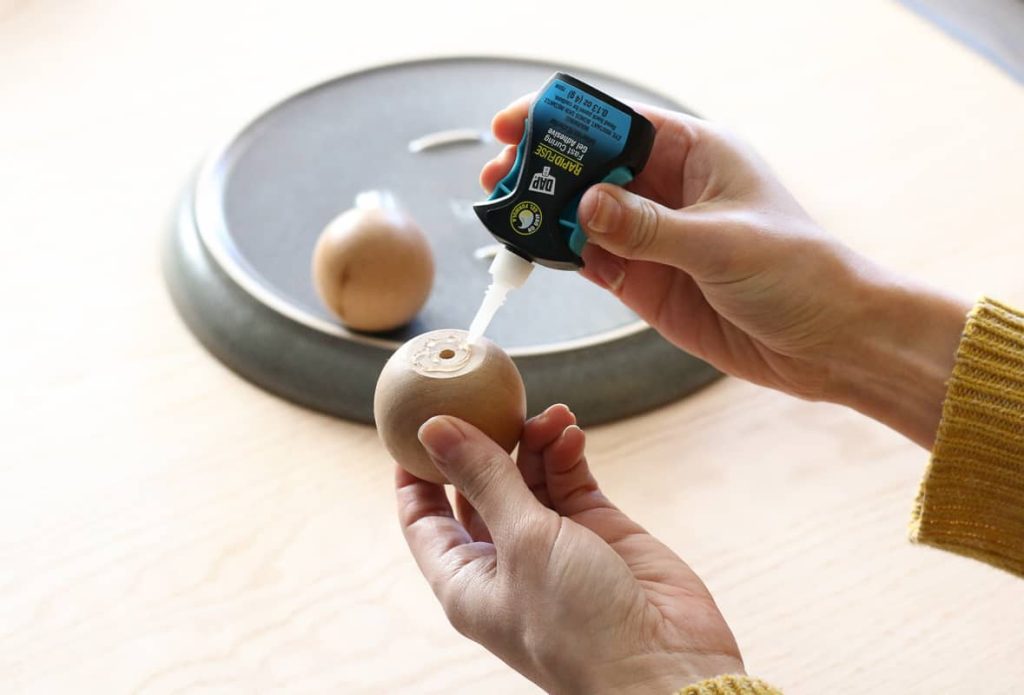 Woman applying DAP RapidFuse Fast Curing with Gel Control Applicator adhesive to wood knob.