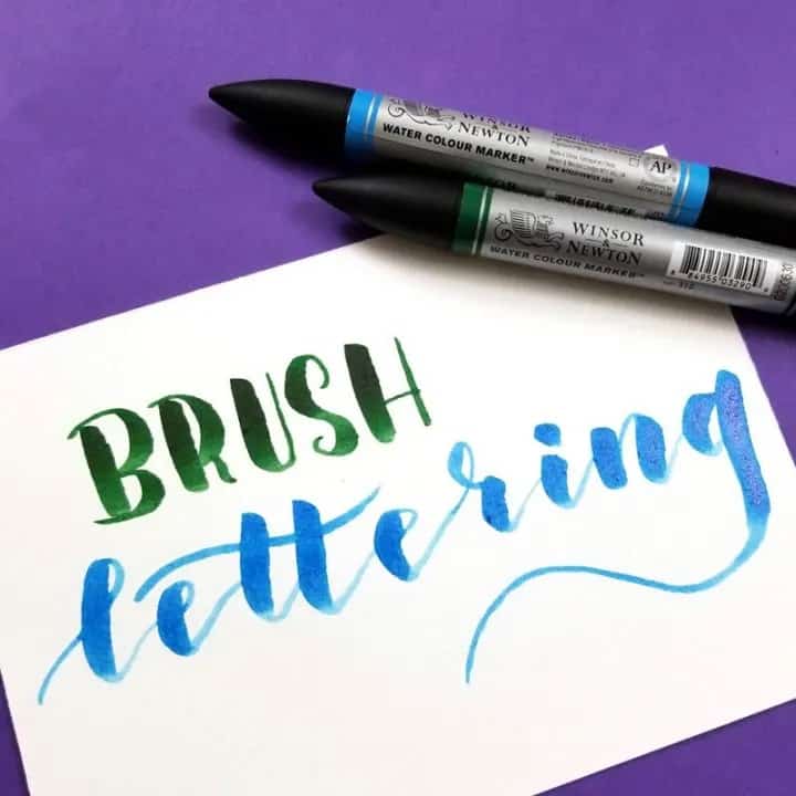 brush lettering, lettered on a piece of paper in green and blue ink