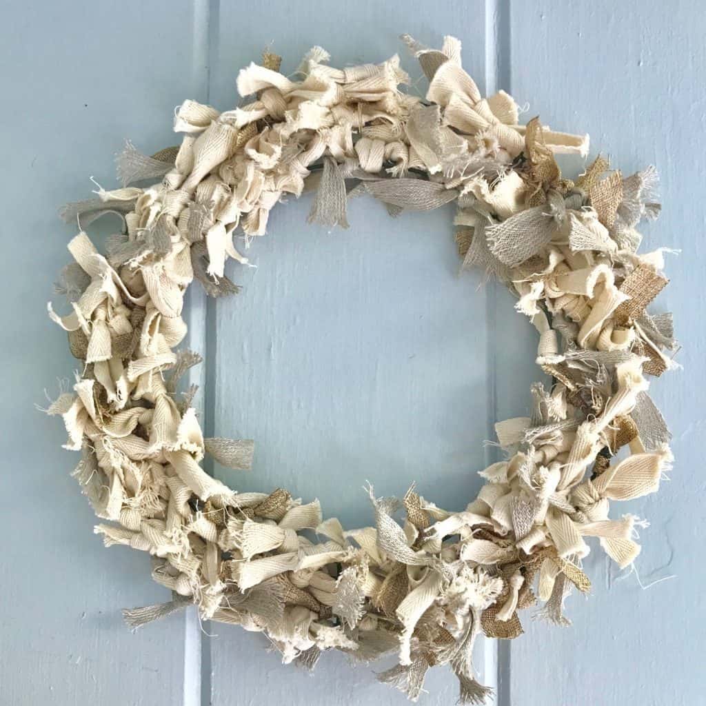 wreath hanging on a door made with neutral colored scraps of rags