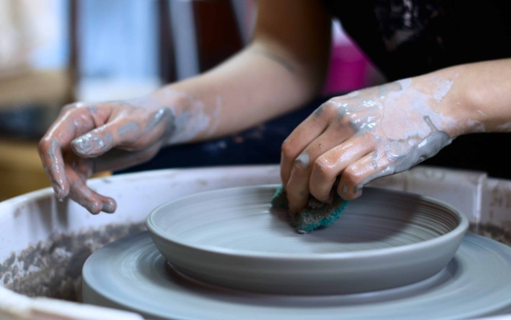 Woman creating pottery on a potters wheel