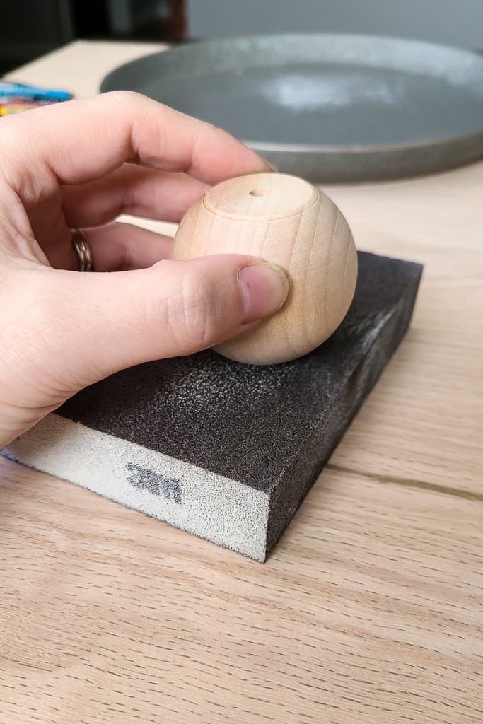 Sanding bottom of wood knob on sanding block.