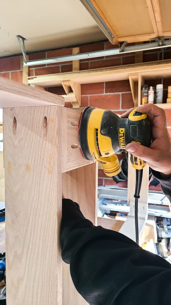 The person is sanding the Behind-the-Couch Table with Outlet.