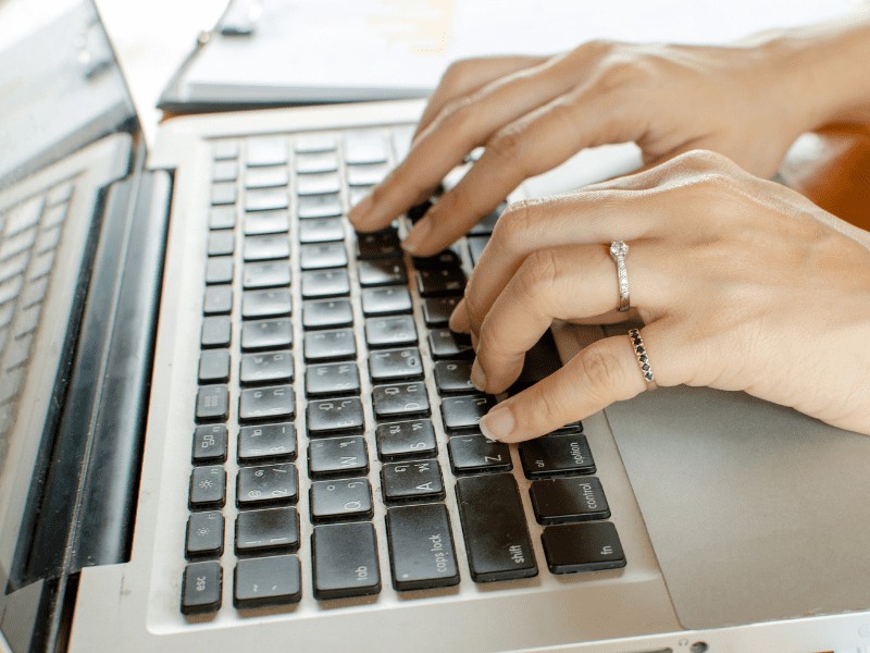 Woman's hands typing on a the keyboard of a laptop.