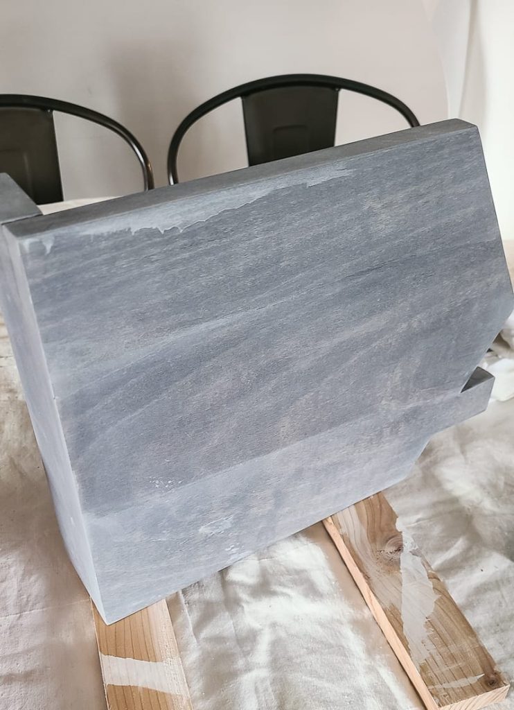 Back of cookbook stand with gray washed wood finish showing imperfection of paint drips.