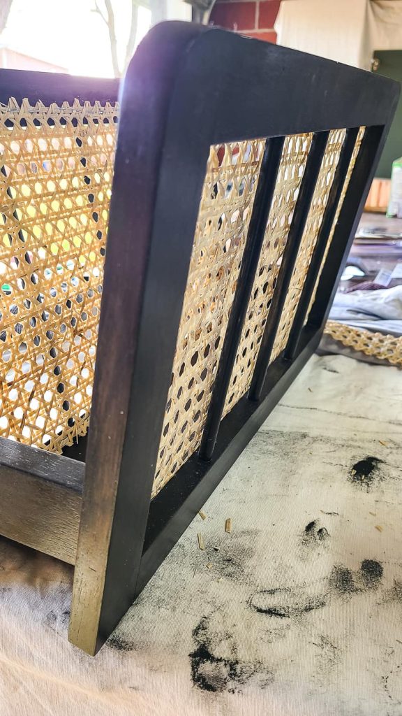 A closeup image showing the newly stained magazine rack with cane webbing in the center. The wood is stained a dark color, and the webbing is a light sand color.