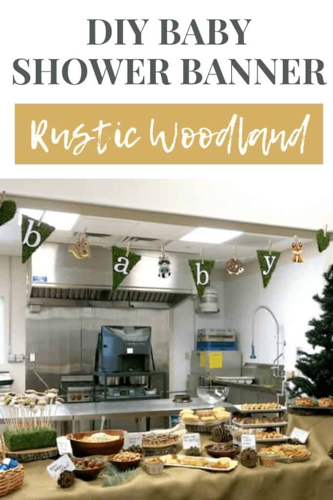 A baby shower banner hangs over a buffet window looking into a restaurant kitchen. The banner is made with faux moss flags with letters that spell out "baby" and little cartoon baby animals between each flag. Text across the top of the image reads "DIY baby shower banner" and "rustic woodland"