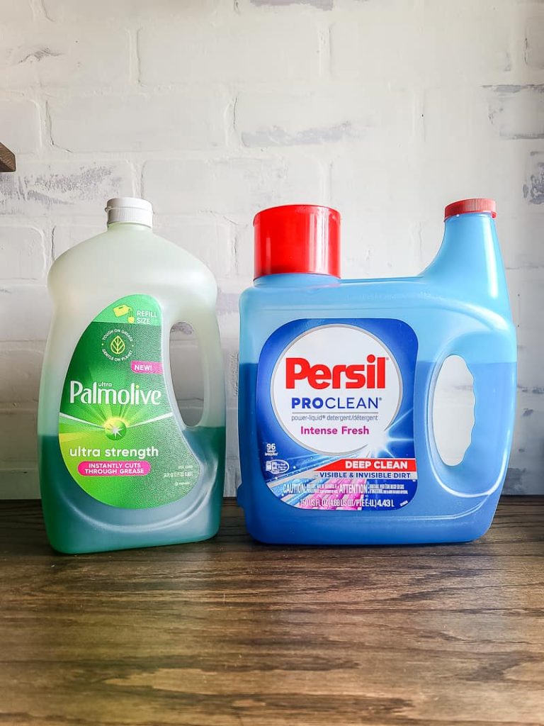Bottle of Palmolive dish soap and jug of Persil laundry detergent sitting on wood counter top.