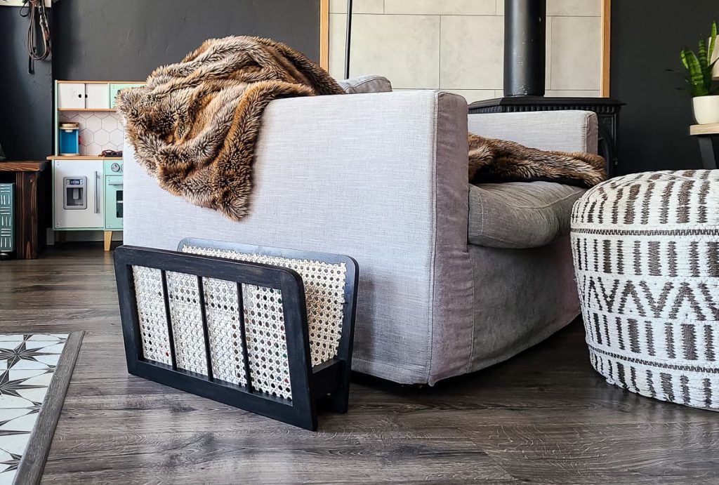 black and cane magazine rack next to gray sofa in living area.