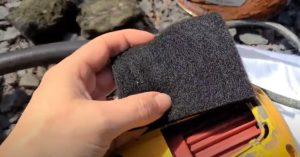A woman holds a brand new filter for a paint gun in her hands. The filter is made of a soft black material.