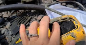 A woman uses her hand and fingers to arrange the new clean filter into the filter compartment of a Wagner paint gun, after removing the old, dirty filter.