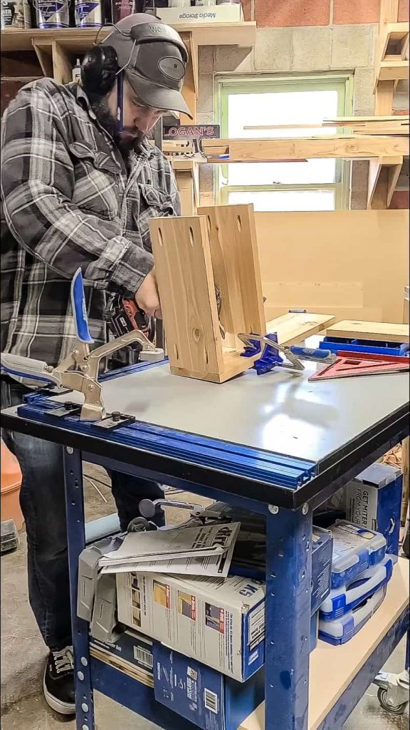 The man assembled the wood to create a grill utensil holder box.