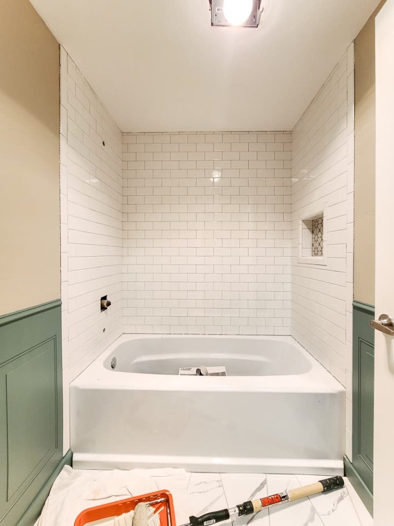View of bathtub with adjacent walls painted a tan color on the top and a green color on the bottom.
