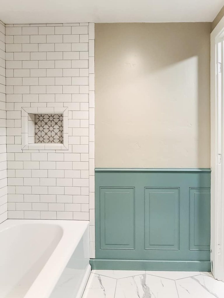 Wainscoting in a bathroom painted green with Behr's In The Moment next to the bathtub.