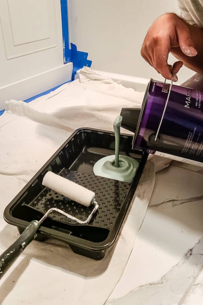 Pouring paint into a paint tray to paint wainscoting panel.