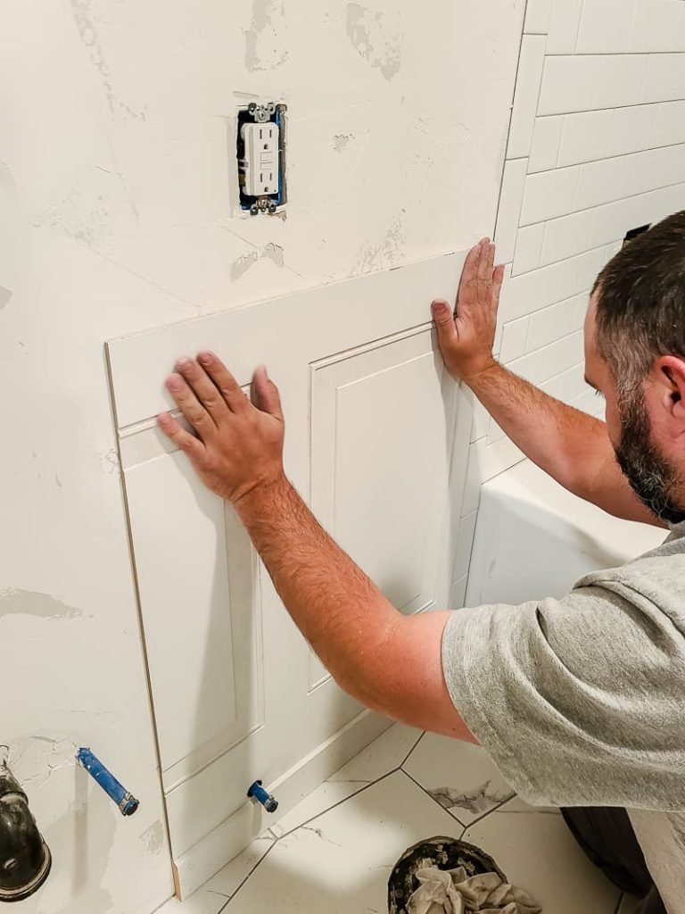 Pressing the wainscoting panel to the bathroom wall.