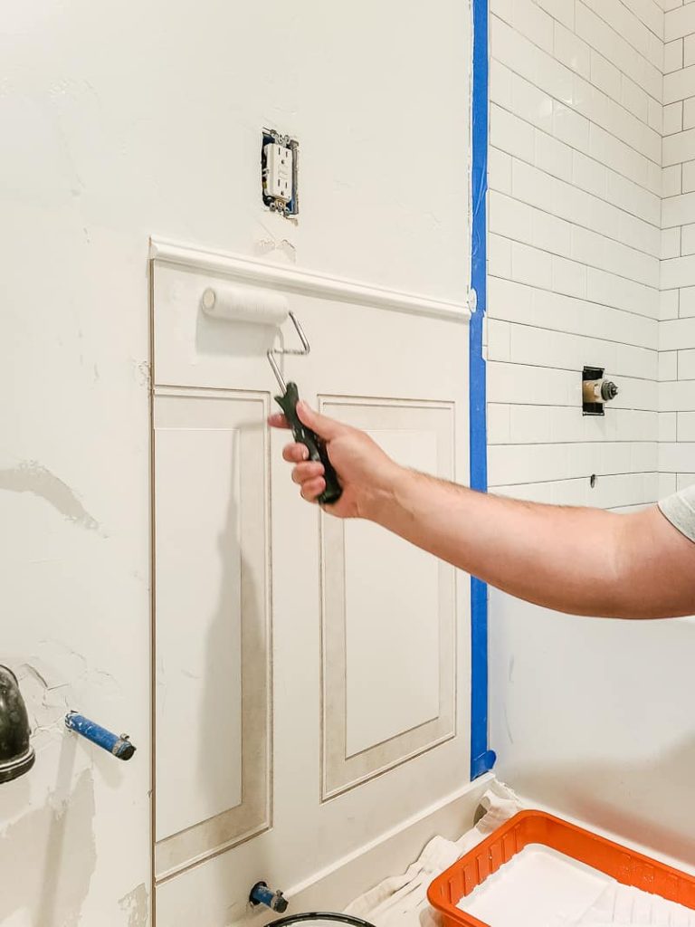 Applying primer to wainscoting panel with a paint roller.