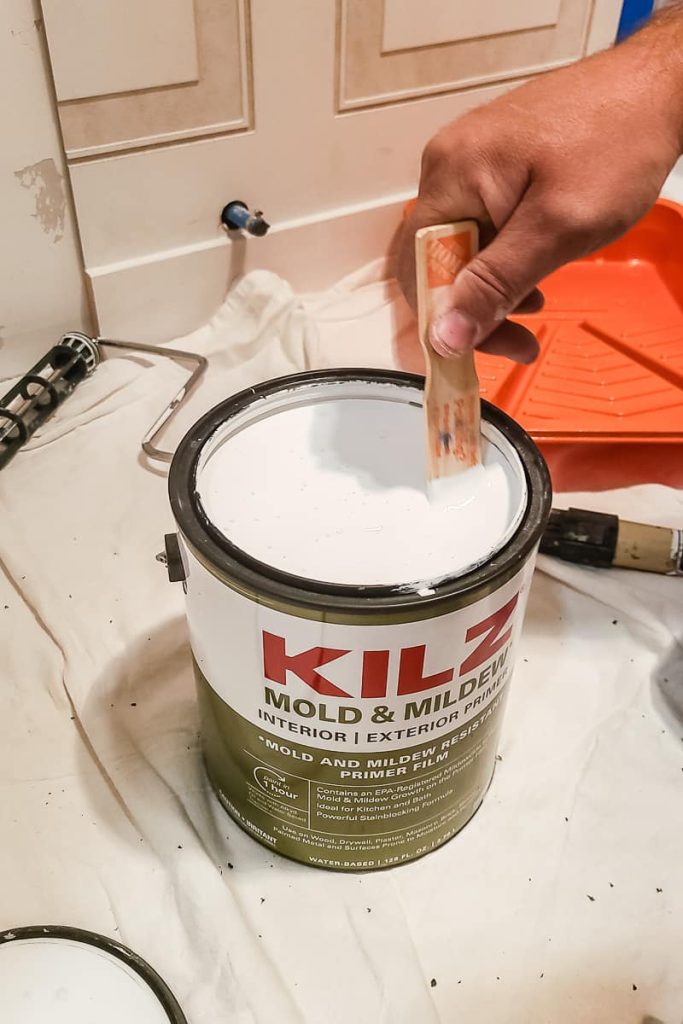 Stirring can of primer for bathroom walls with stir stick.
