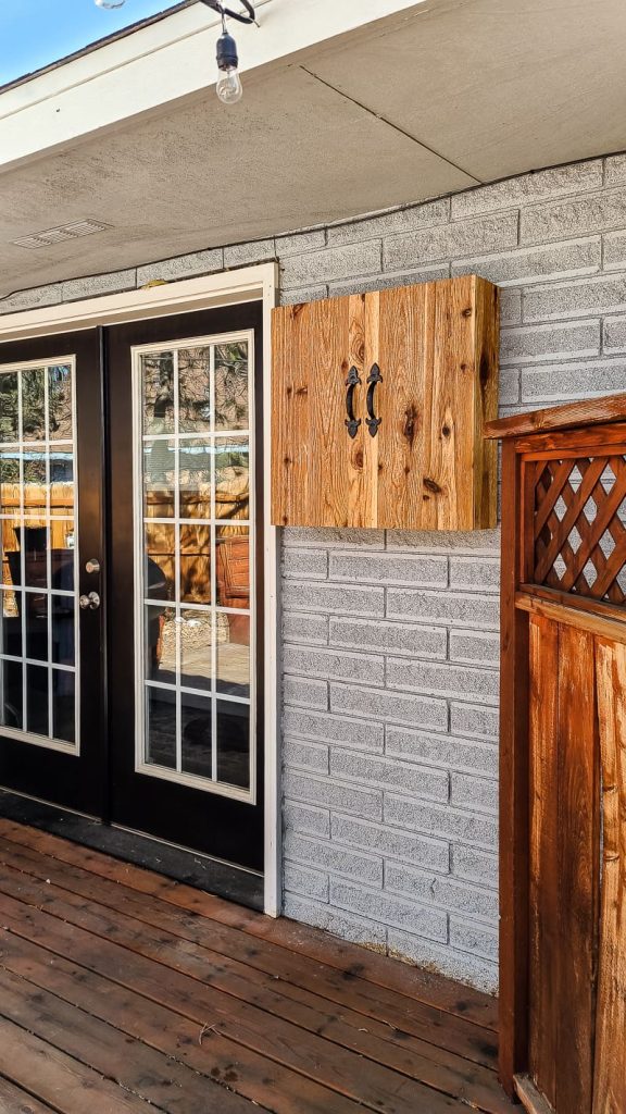 Cabinet mounted on the outside of the house next to french doors into bricks