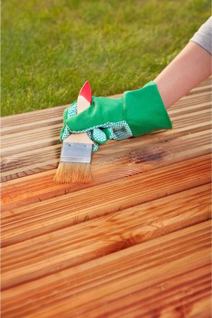 Applying deck oil to the boards of a deck with a paint brush will enhance the color of the boards and protect against moisture and UV rays.