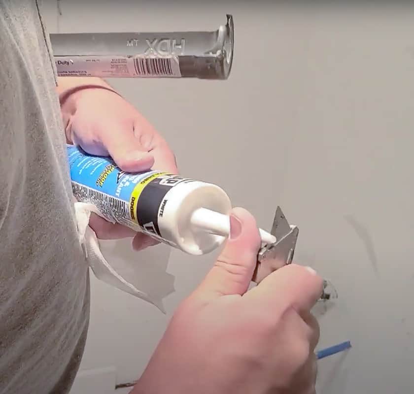 To load a caulking gun, start by cutting the tip of the caulking tube at a 45° angle with a utility knife. 