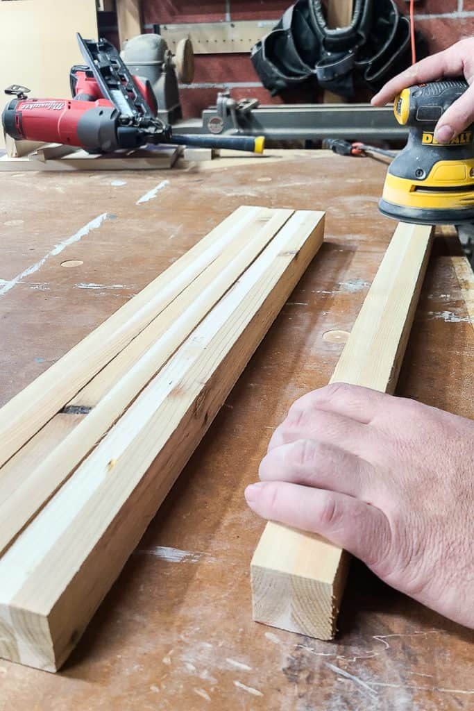 Photo of someone sanding the legs for crafting the Outdoor Toy Deck Box.