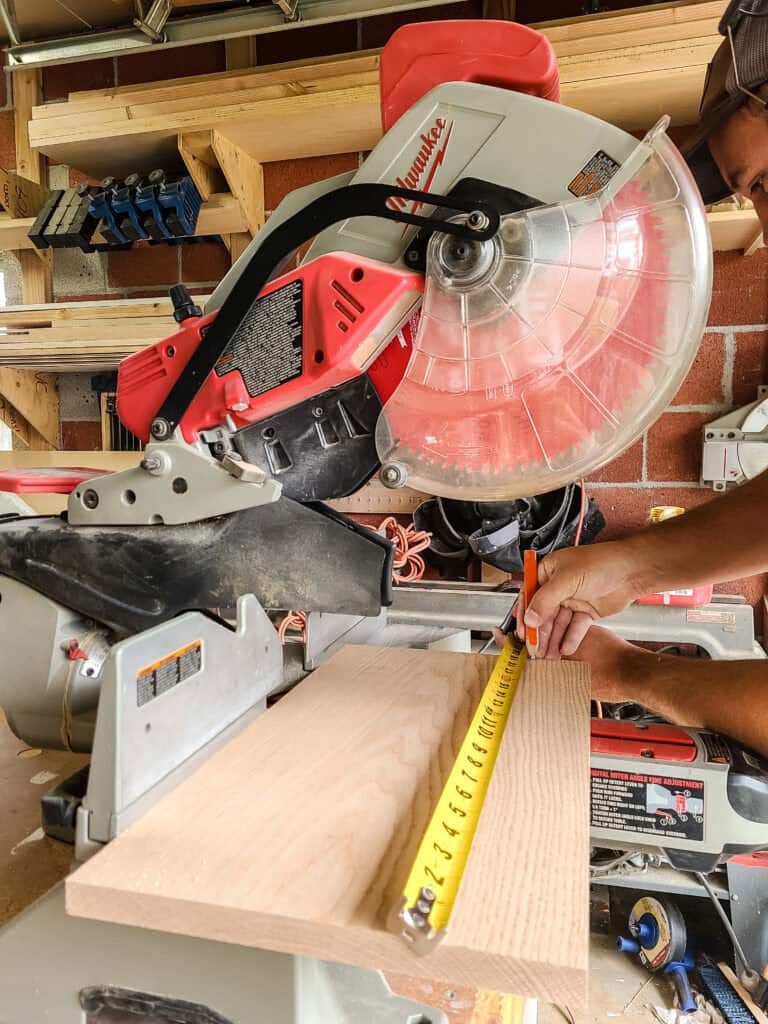 Cutting wood down to size for wooden towel shelf with miter saw 