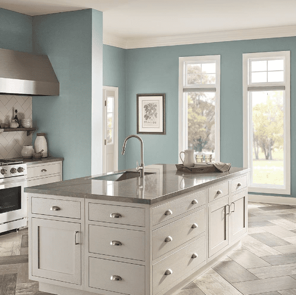 Rainy Afternoon by Behr Paint is a beautiful option if you're looking for a gray-green paint color with blue undertones. We love the green gray blue painted walls in this airy kitchen with light cabinets, gray countertops and herringbone tile floors. The mixture of blue, green, and gray together make this paint color interesting and complex. 