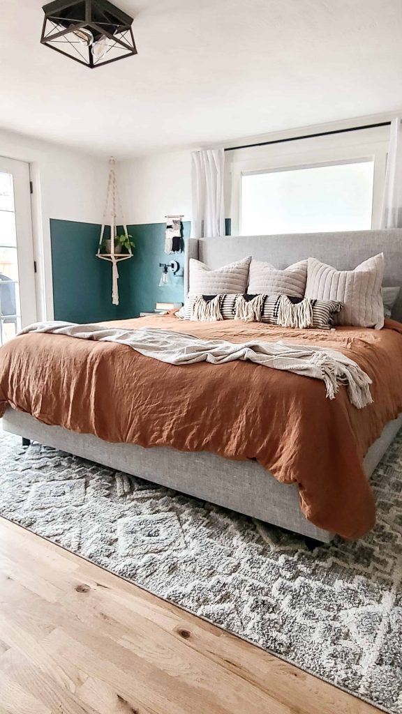 View of bed with Terra colored duvet cover, natural colored textured throw, boho black and white lumbar throw pillow and three Euro style pillows with velvet pillow covers.