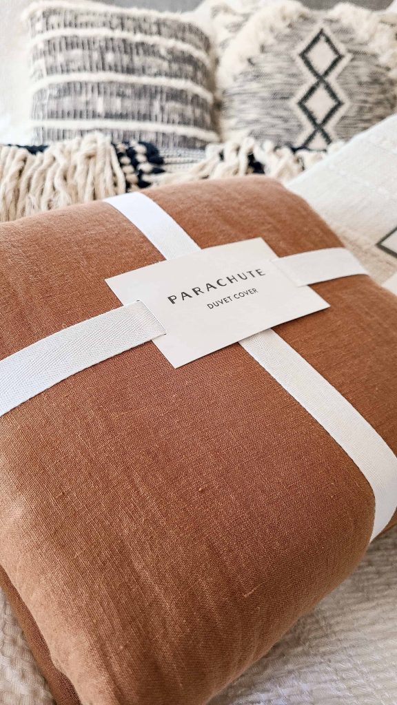 A close up image of a brand new duvet cover still in the store packaging. The brand is Parachute and the duvet is a rich rusty brown color.