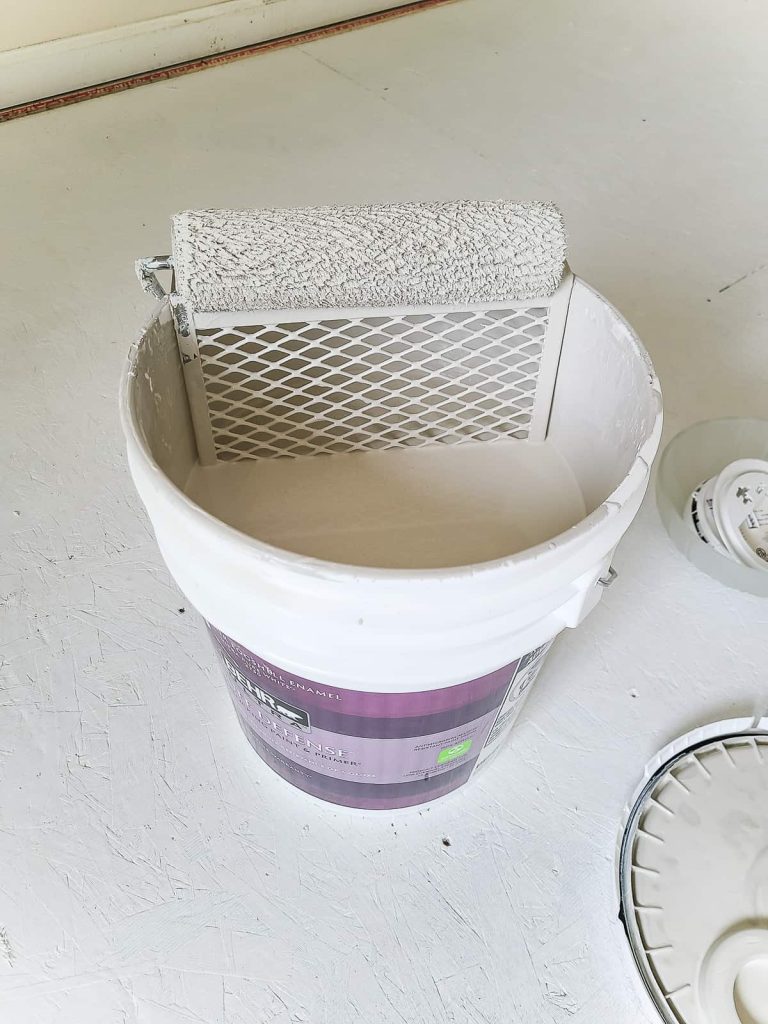 Another photo of paint in a 5 gallon bucket and a roller brush.