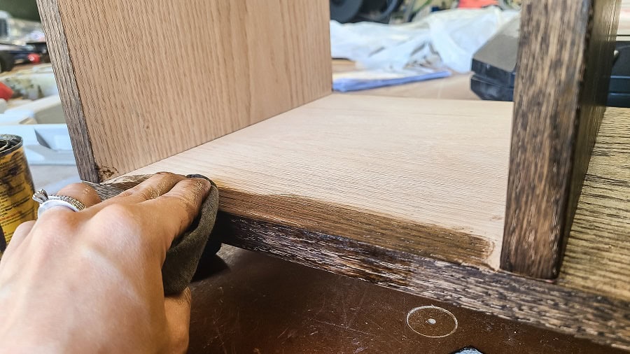 Applying dark wood stain to wooden towel shelf for bathroom