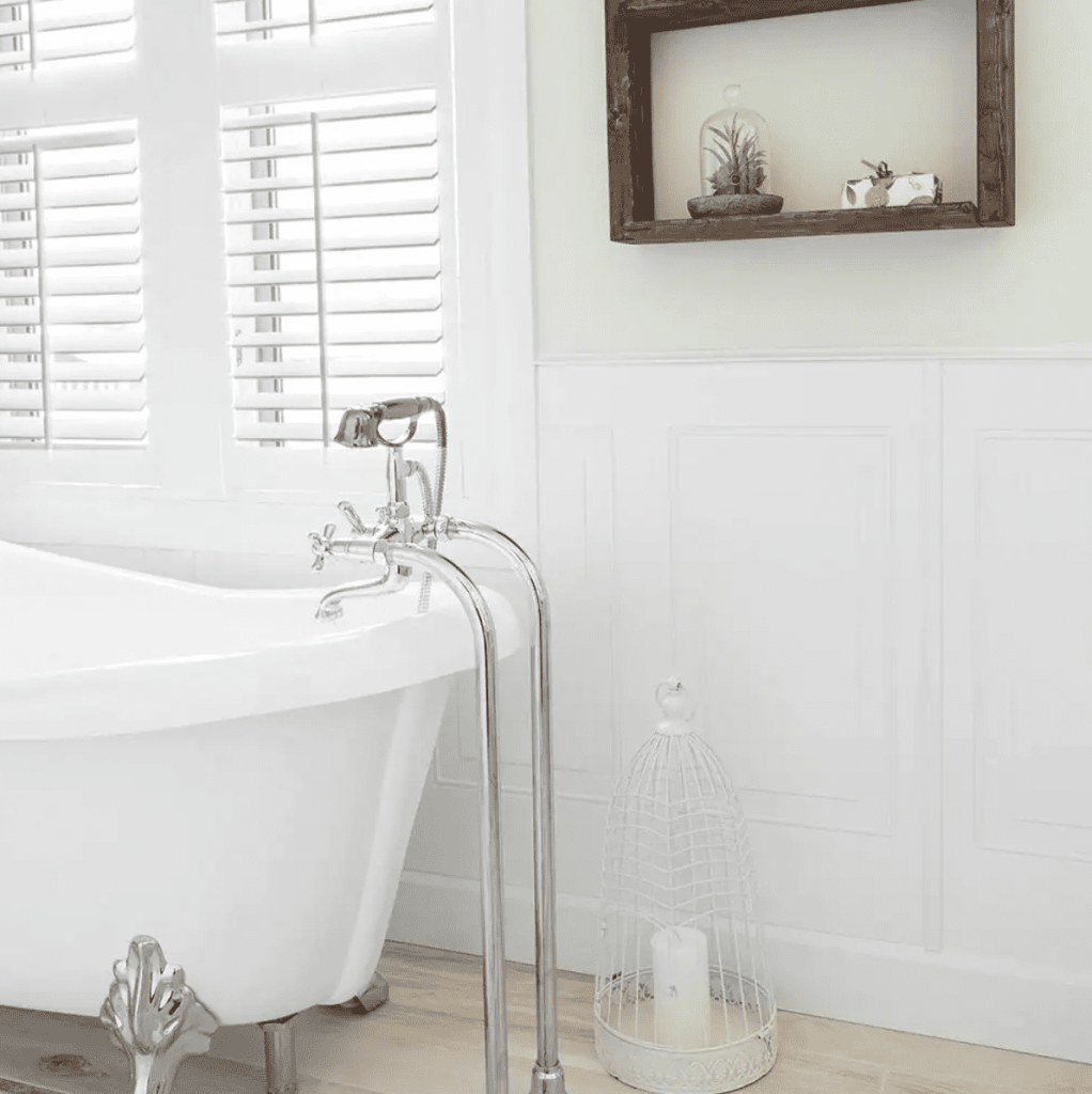 Wainscoting feature painted white next to freestanding white bathtub.