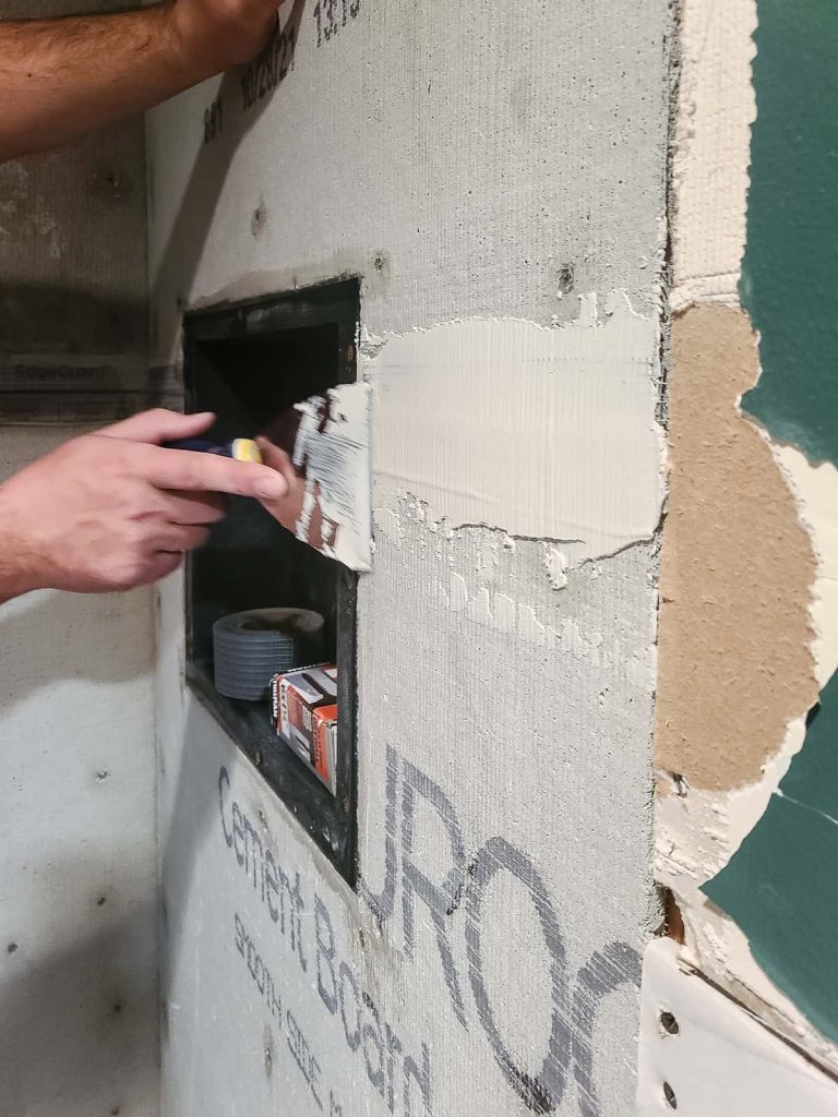 Applying mortar of cement board seams  on the shower wall