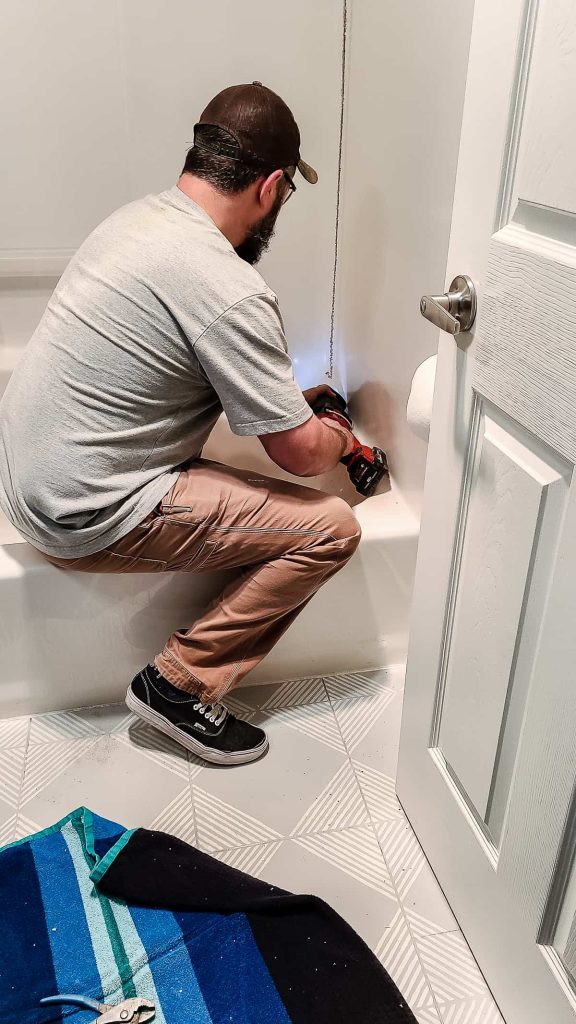 Using a reciprocating saw to remove cut through the old tub surround for removal.