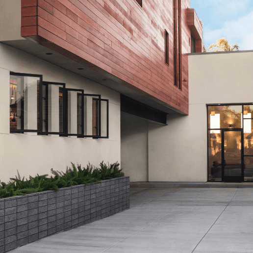 This warm beige color, called Even Better Beige, from Behr Paint looks great painted on the exterior of this modern home with wood paneling accents and black frame windows. 