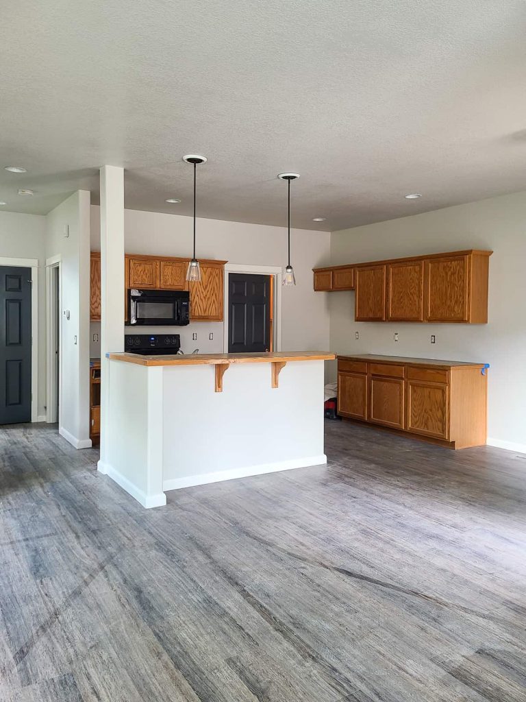 This living and kitchen area with honey oak cabinets and kitchen island looks great painted with a beige paint color