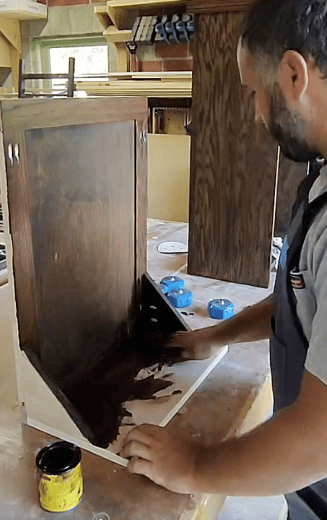 Applying dark walnut wood stain to trash cabinet for kitchen