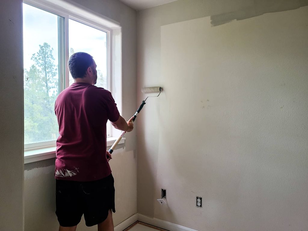 Man painting the wall with a paint roller