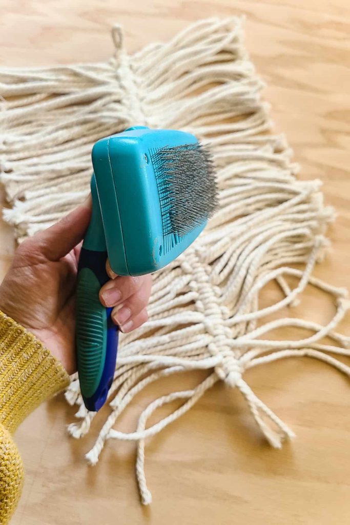 Closeup of a pet hairbrush to be used to comb out the macrame cord to make the macrame feather