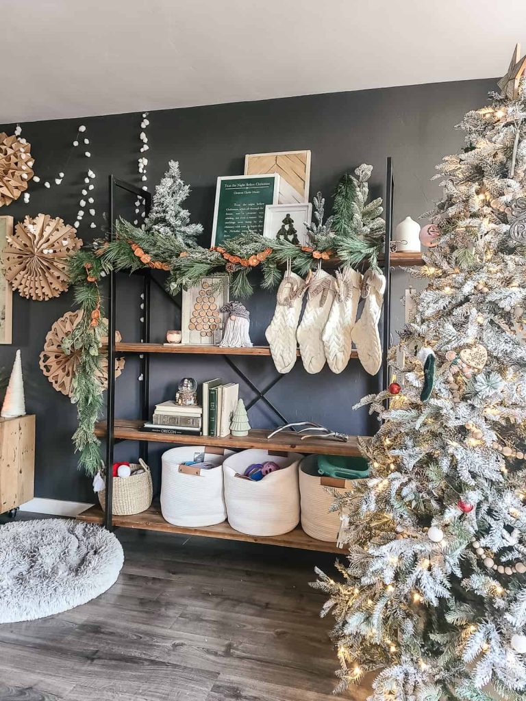 Shelving unit in living room decorated for Christmas with stockings hung on the shelves, which is a great way to display stockings if you don't have a fireplace with a mantel