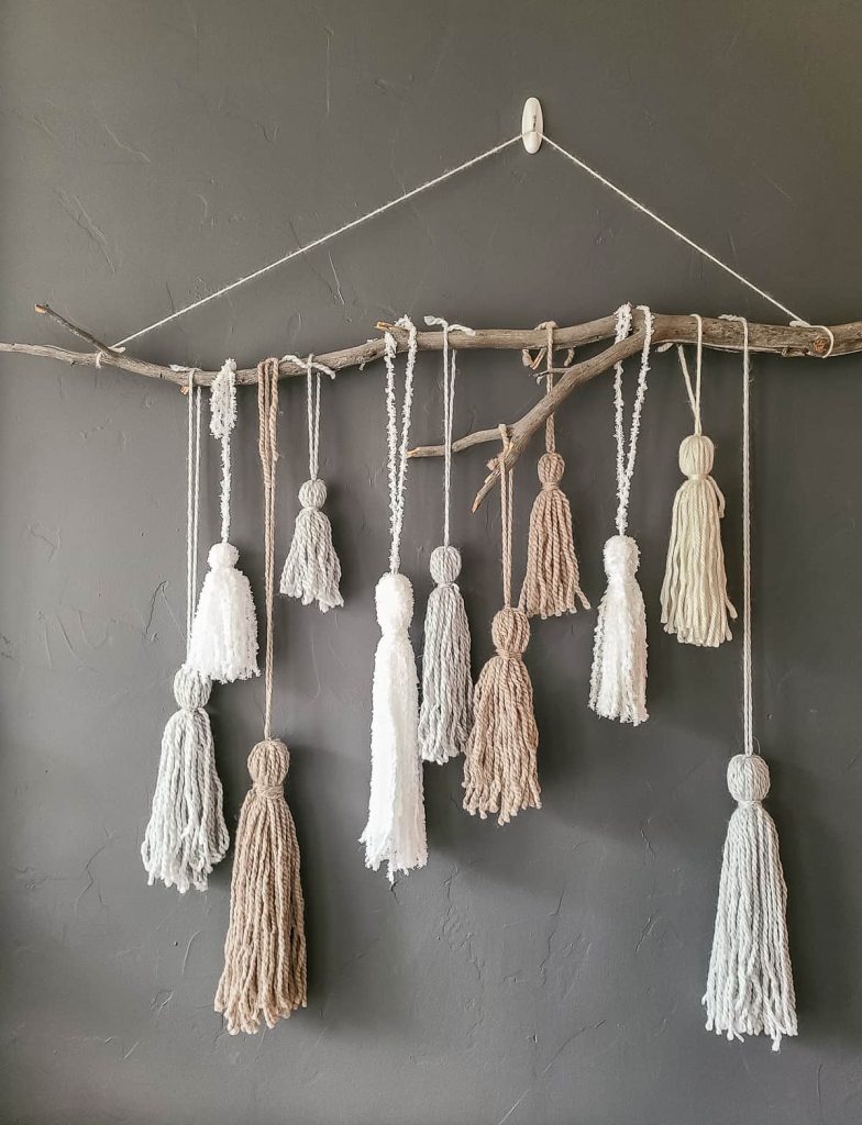 I love these yarn tassels look hanging on the wall from this stick