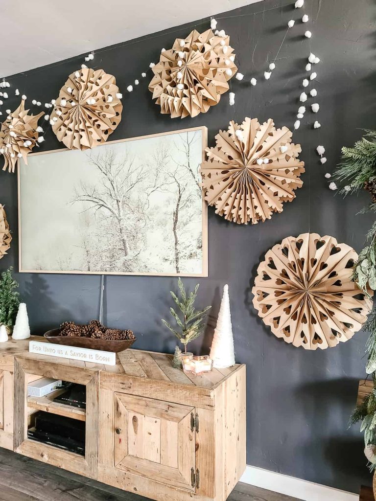 Cotton ball garland strung up onto wall with giant paper snowflakes around TV