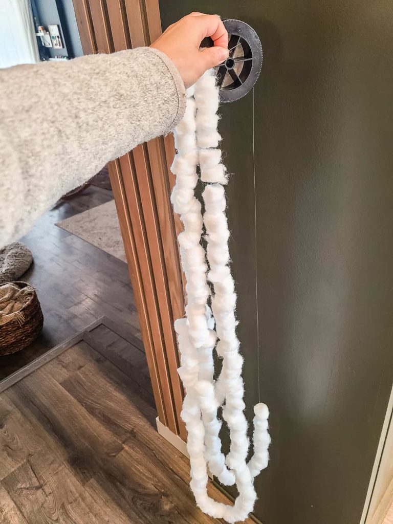 Woman's hand holding up a bunch of cotton balls strung onto fishing line